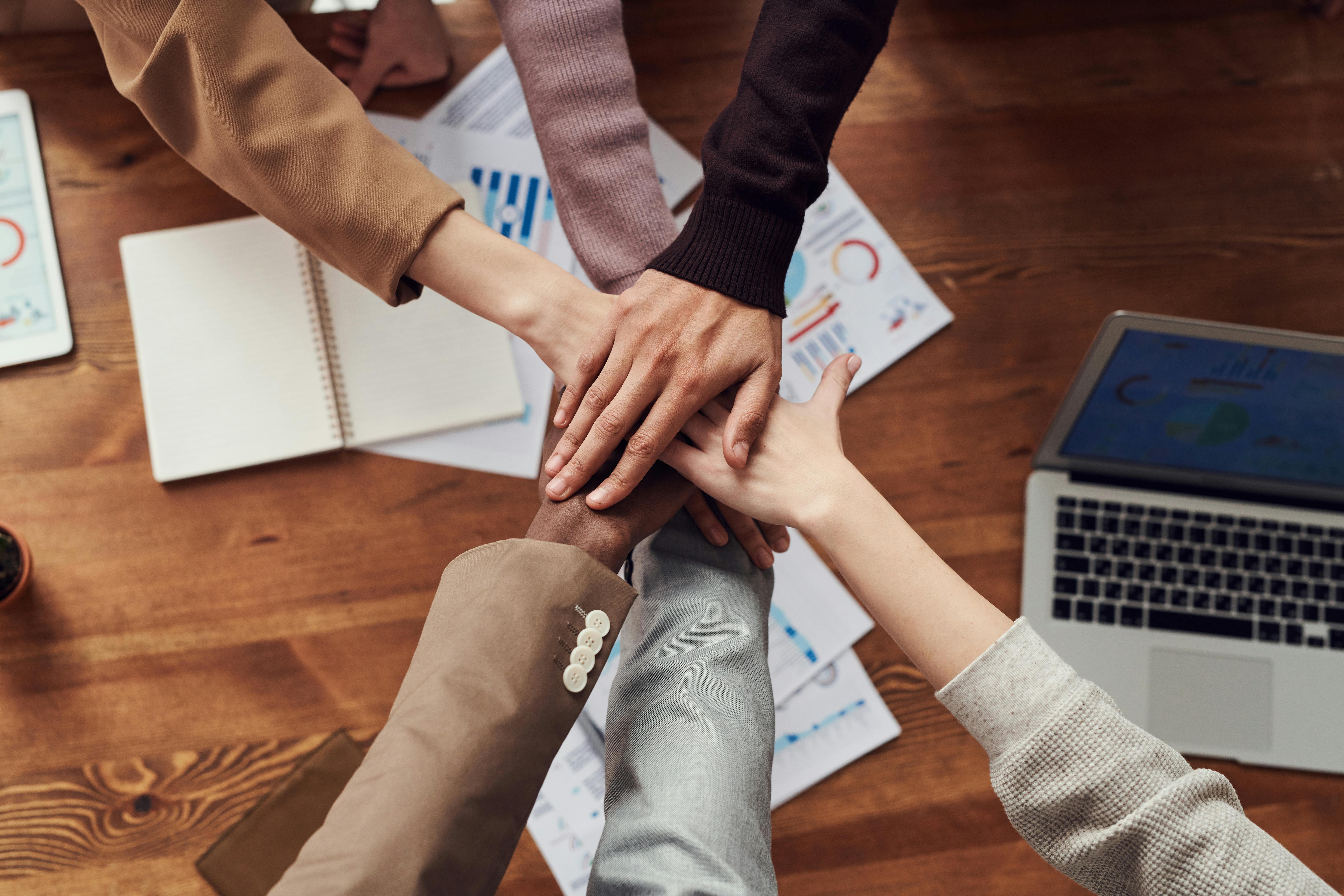 Team members putting their hands into a circle